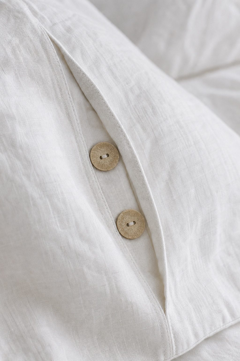 A hidden placket with small corozo buttons on a white linen pillowcase